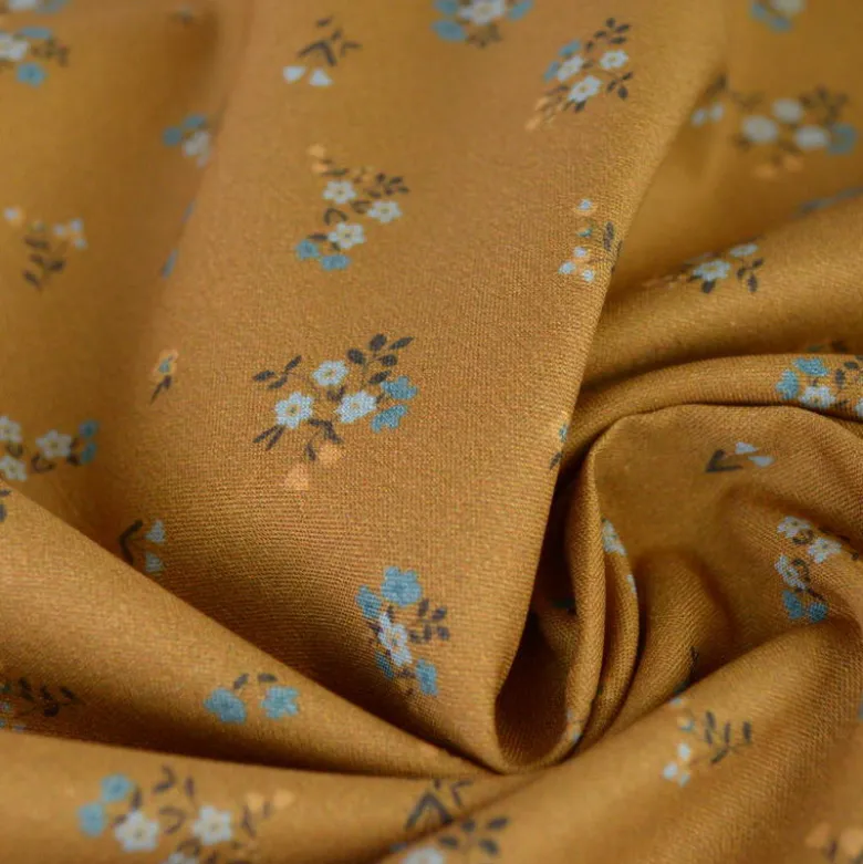 Popeline de coton Bisou motif fleurs bleues fond Ocre