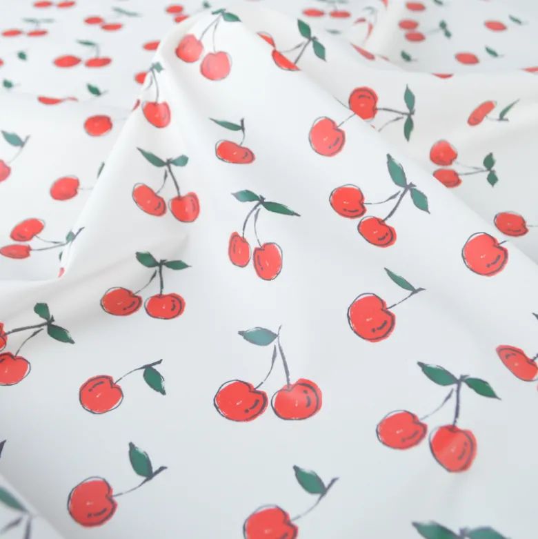 Tissu imperméable type ciré motif cerises fond blanc