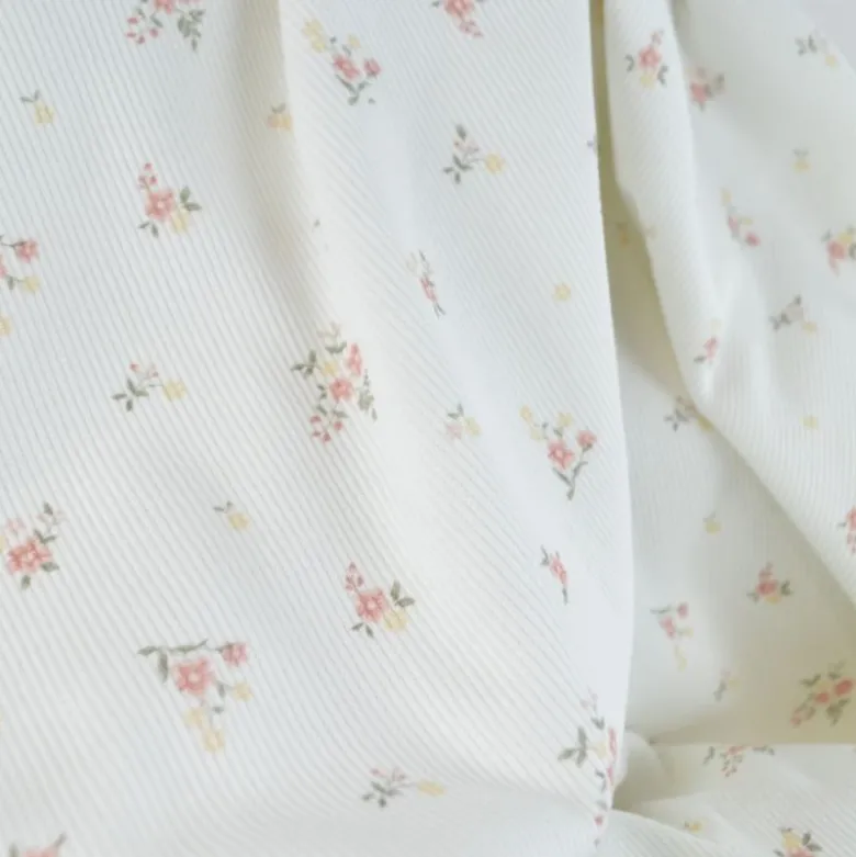Tissu jersey côtelé motif fleurs roses fond blanc cassé