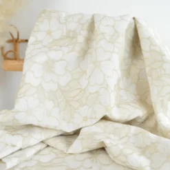 Tissu voile de coton brodé beige motif fleurs fond sable