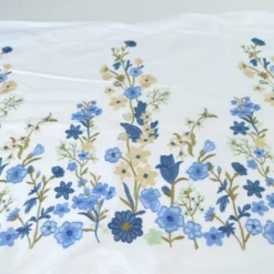 Voile de coton brodé de fleurs bleues et beige fond blanc