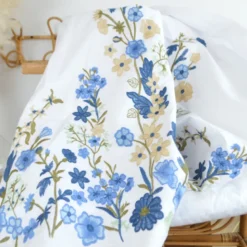 Voile de coton brodé de fleurs bleues et beige fond blanc