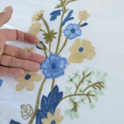 Voile de coton brodé de fleurs bleues et beige fond blanc